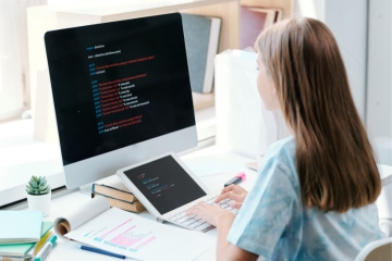 A student with long hair coding on a computer, wit