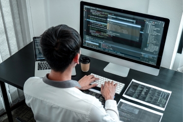 Programmer coding at desk with monitors